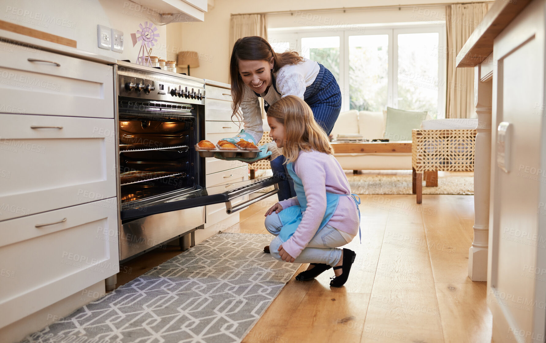 Buy stock photo Shot of a mother and daughter inserting a tray of cupcakes into the oven