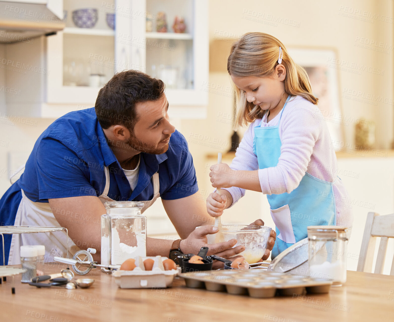 Buy stock photo Shot of a young man helping his daughter stir a bowl of cake batter