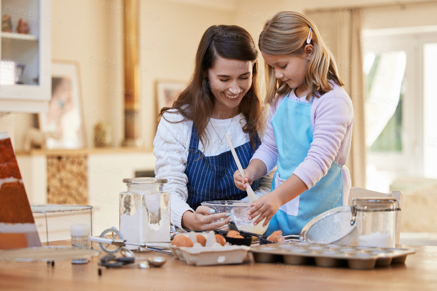 Buy stock photo Shot of a young woman helping her daughter stir a bowl of cake batter