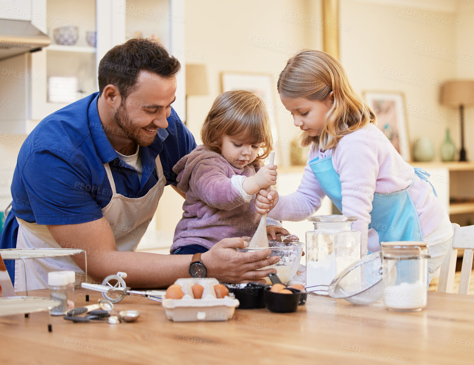 Buy stock photo Shot of a young father baking together while a little girl stirs a bowl of cake batter
