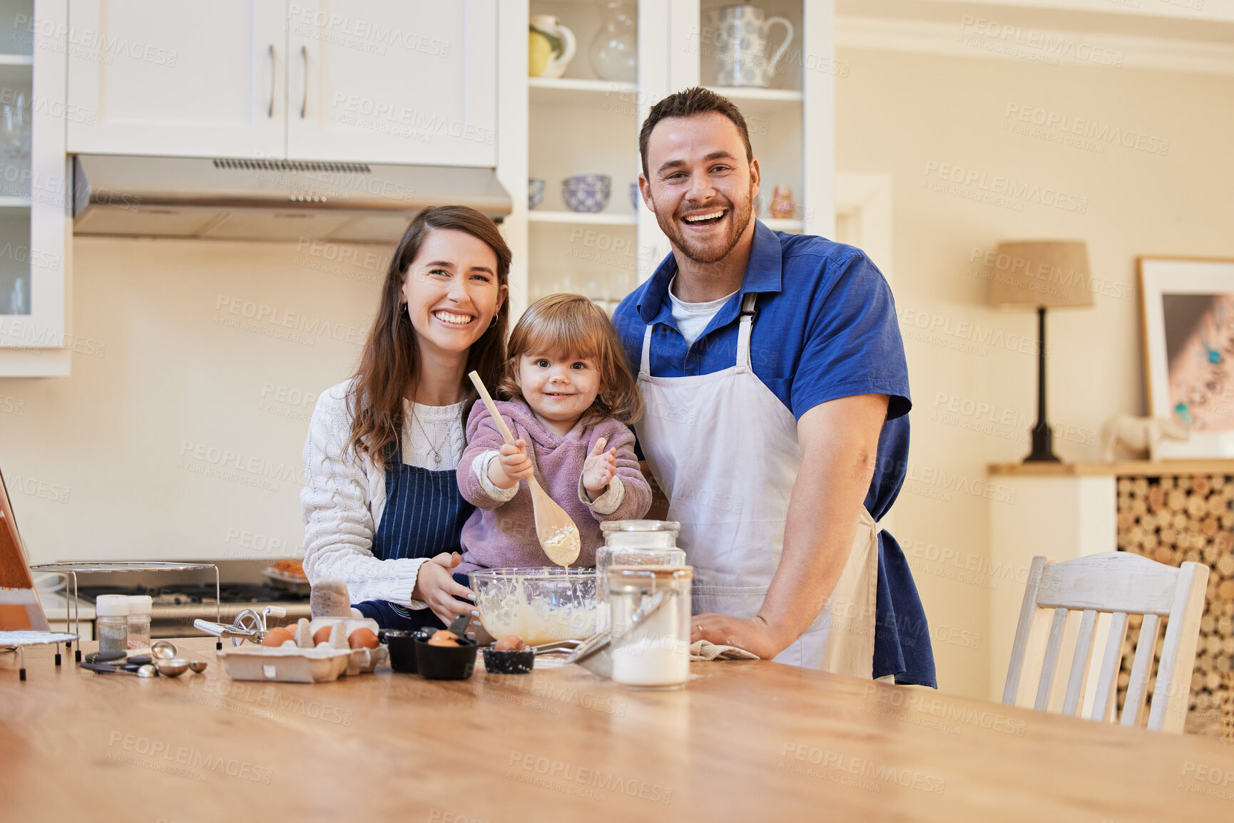 Buy stock photo Shot of a family baking together while a little girl stirs a bowl of cake batter