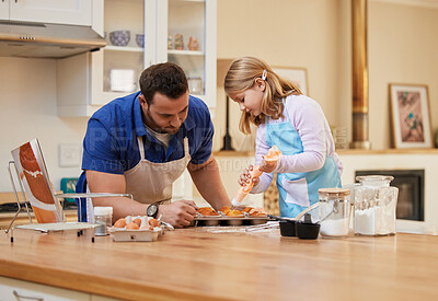 Buy stock photo Shot of a young man helping his daughter frost freshly baked cupcakes