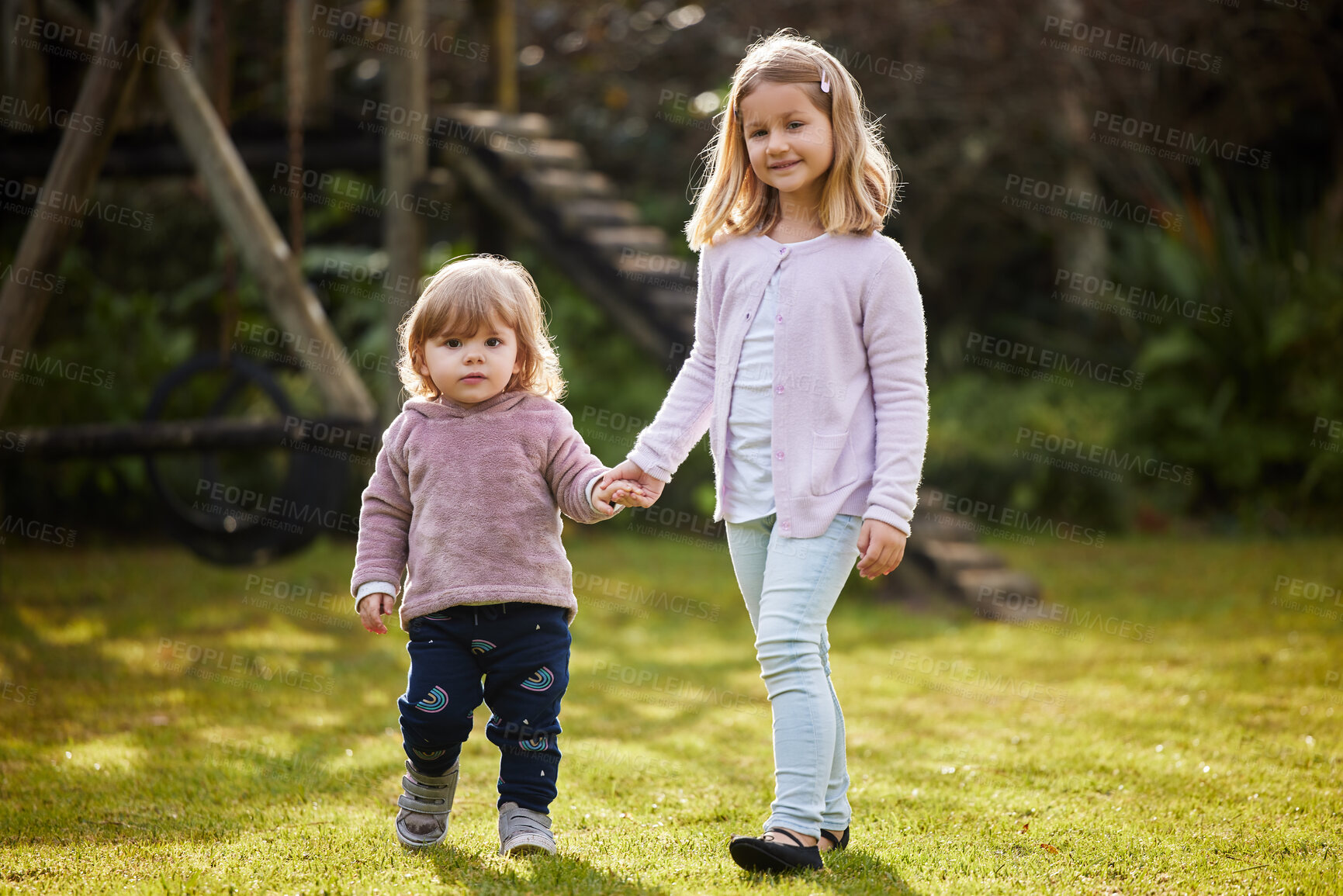 Buy stock photo Full length portrait of two adorable little sisters standing hand in hand in the garden at home