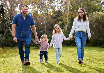 Buy stock photo Full length portrait of an affectionate young family of four walking hand in hand in the garden at home