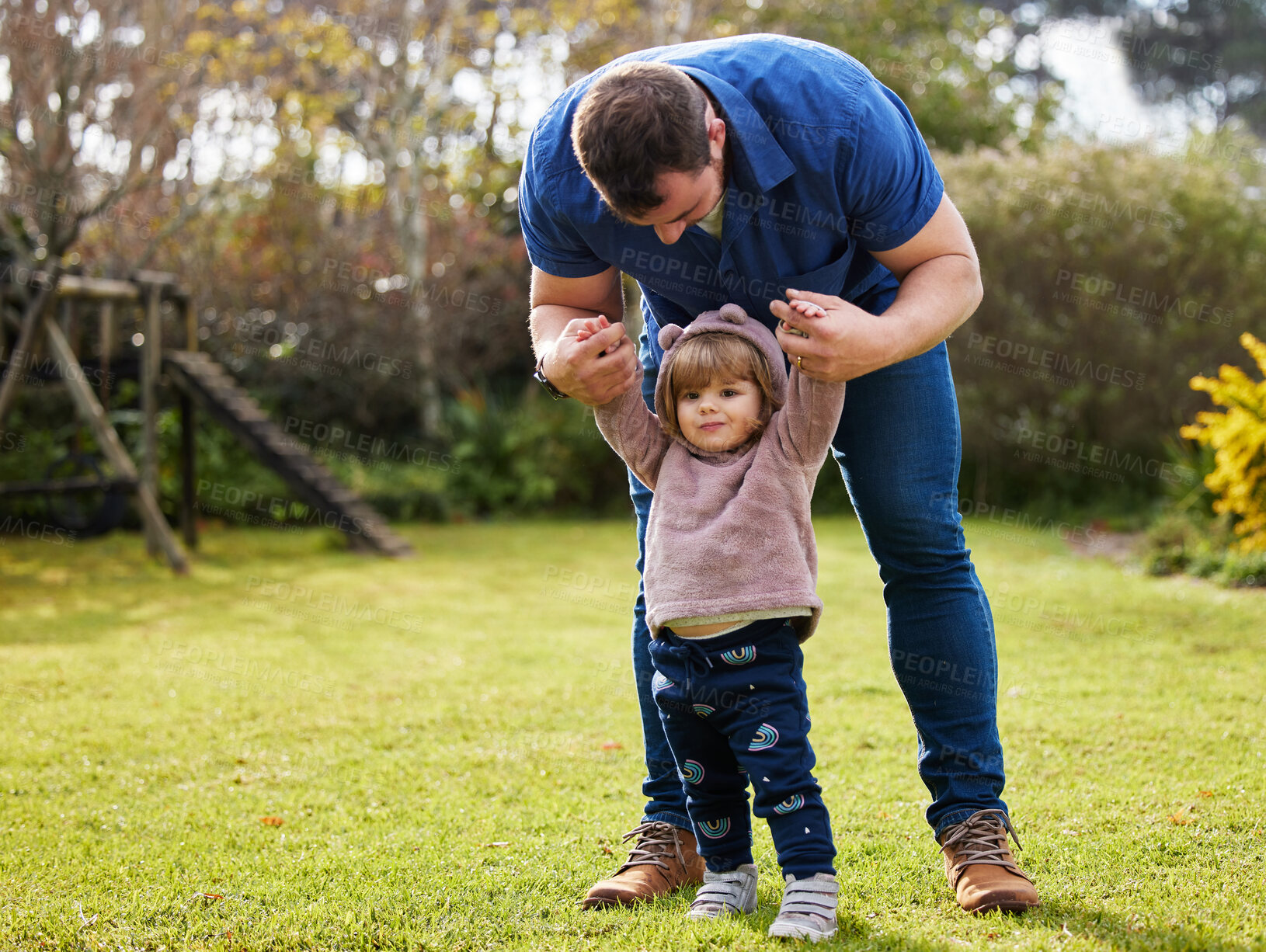 Buy stock photo Full length shot of an adorable little girl and her father standing outside in the garden at home