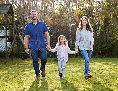 Buy stock photo Full length portrait of an affectionate young family of three walking hand in hand in the garden at home