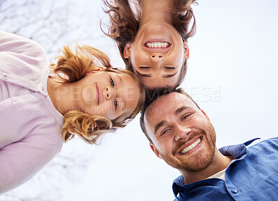 Buy stock photo Low angle portrait of an affectionate young family of three huddle together outside  in the garden at home