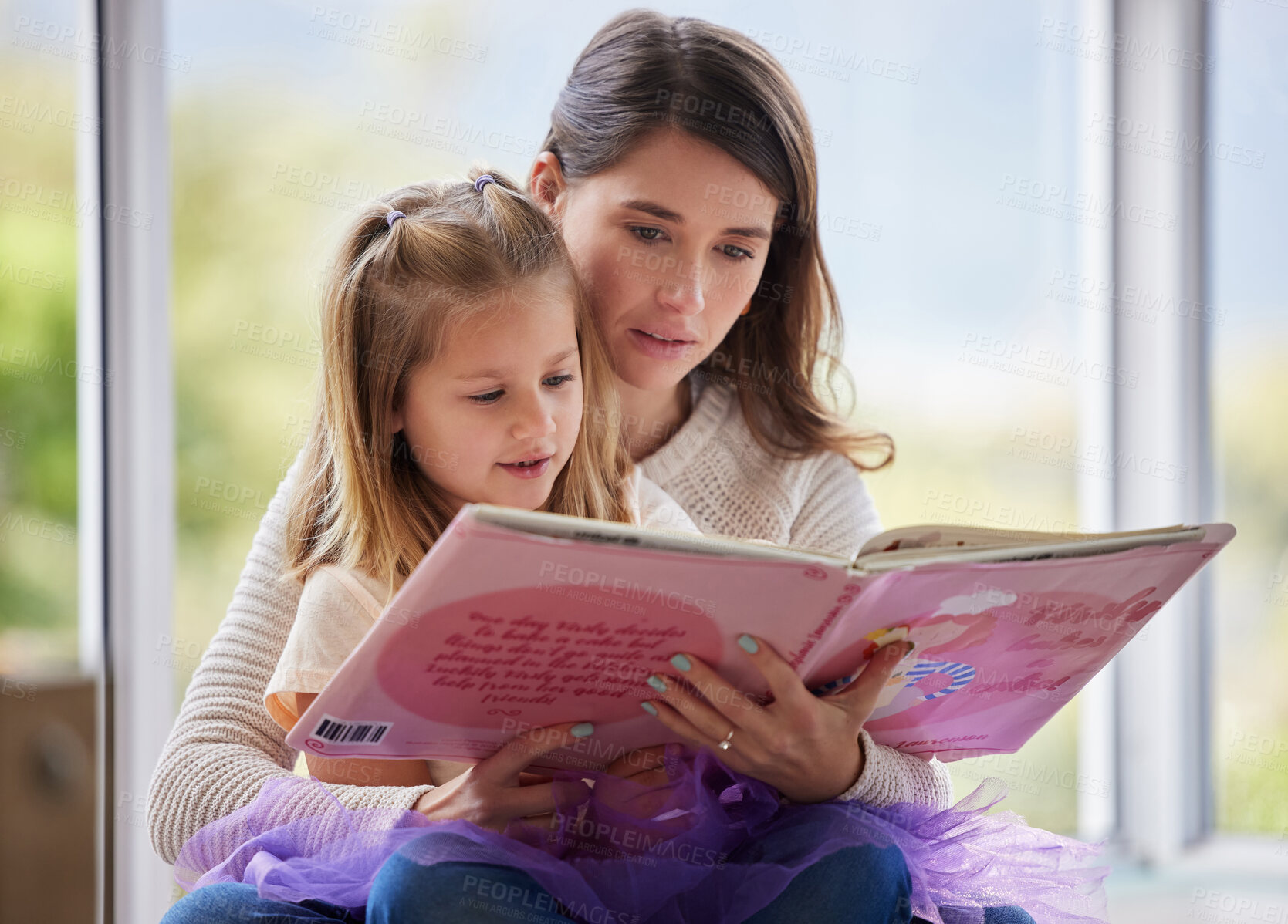 Buy stock photo Shot of a young mother reading a book with her daughter at home