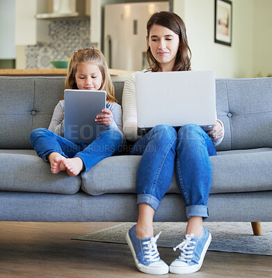 Buy stock photo Shot of a young mother and daughter using a laptop and digital tablet on the couch at home