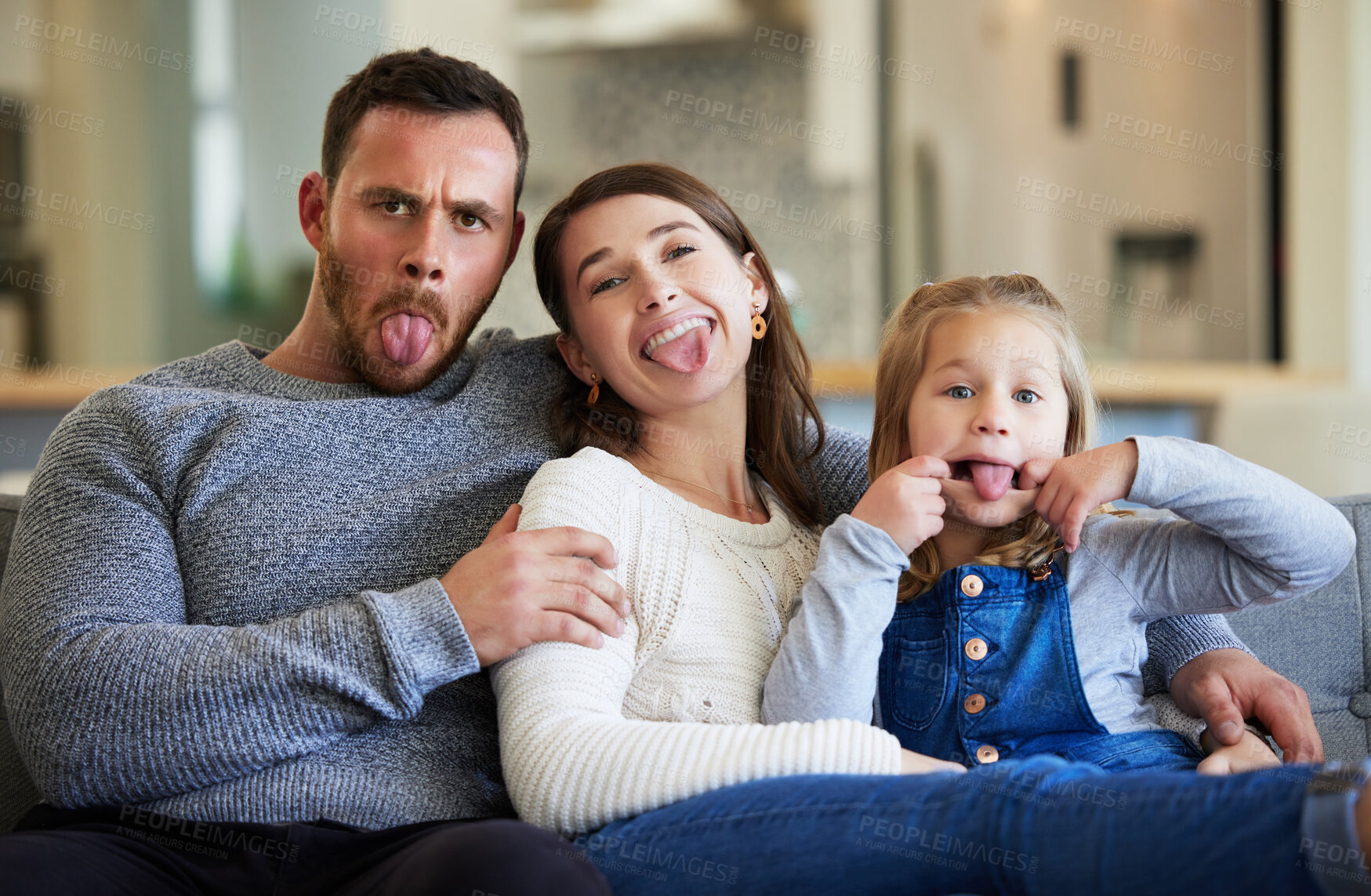 Buy stock photo Shot of a young famiily making funny faces on the couch at home