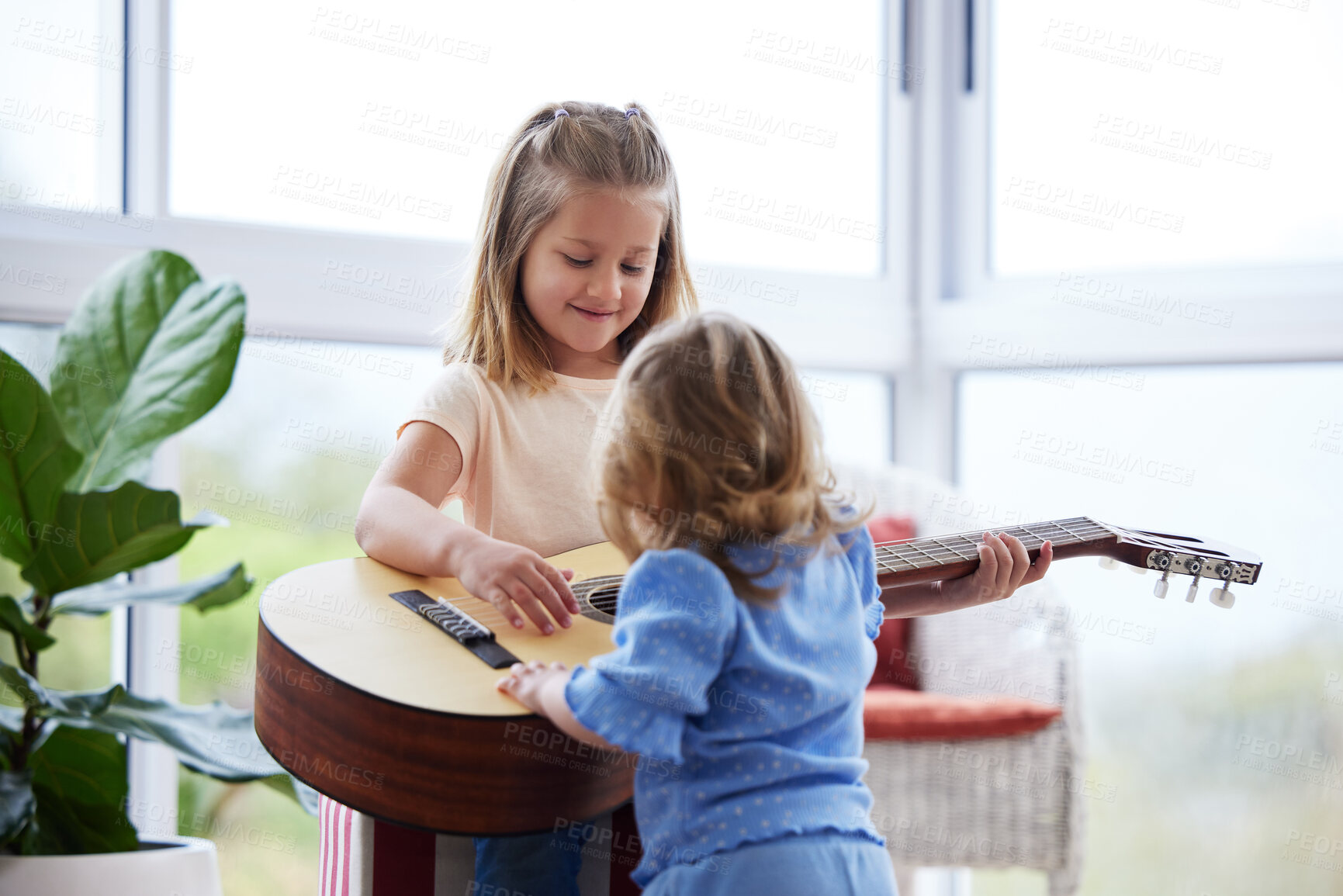 Buy stock photo Shot of two little sisters playing the guitar at home