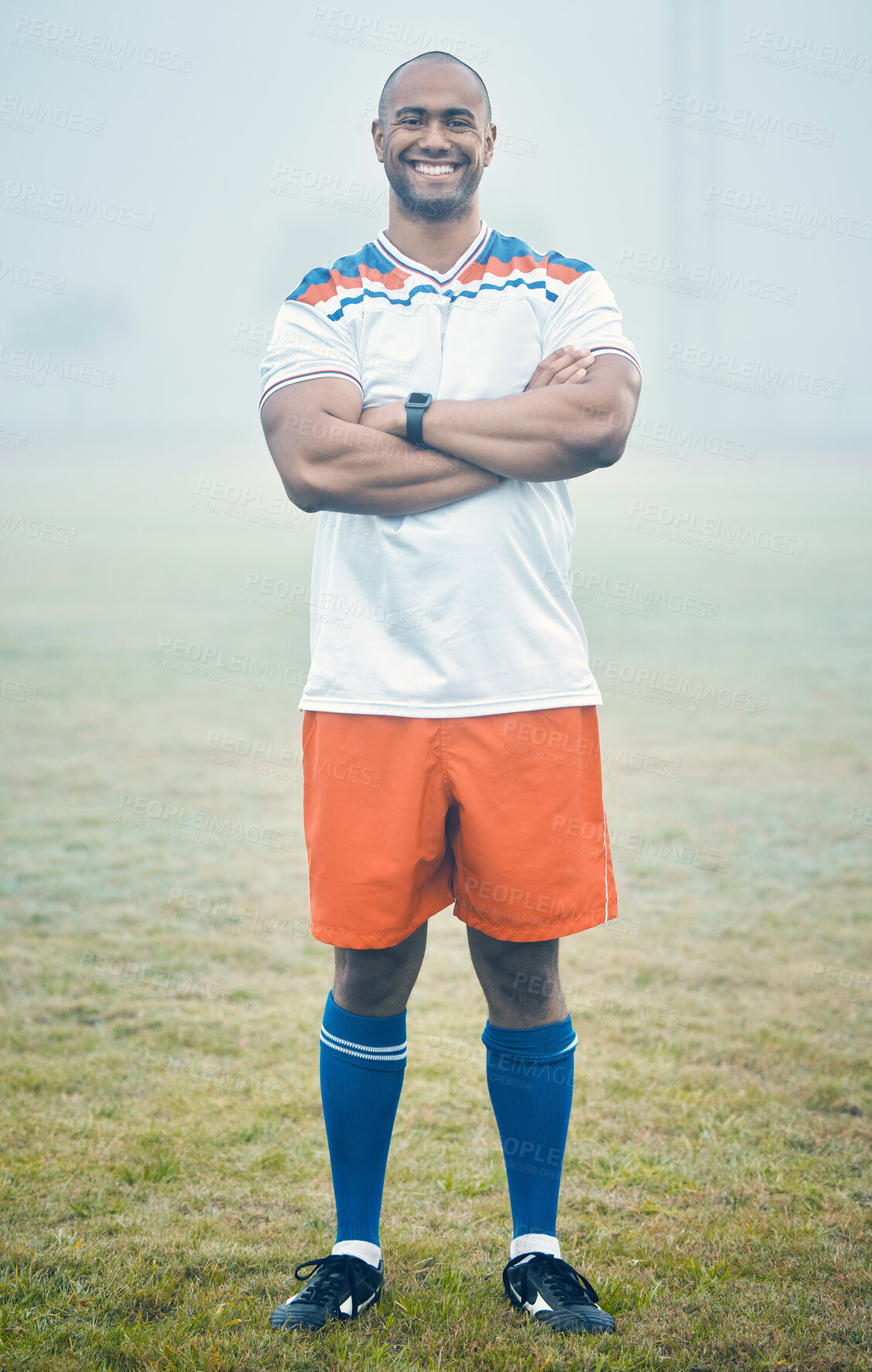 Buy stock photo Shot of a young sportsman standing on the field during a misty morning