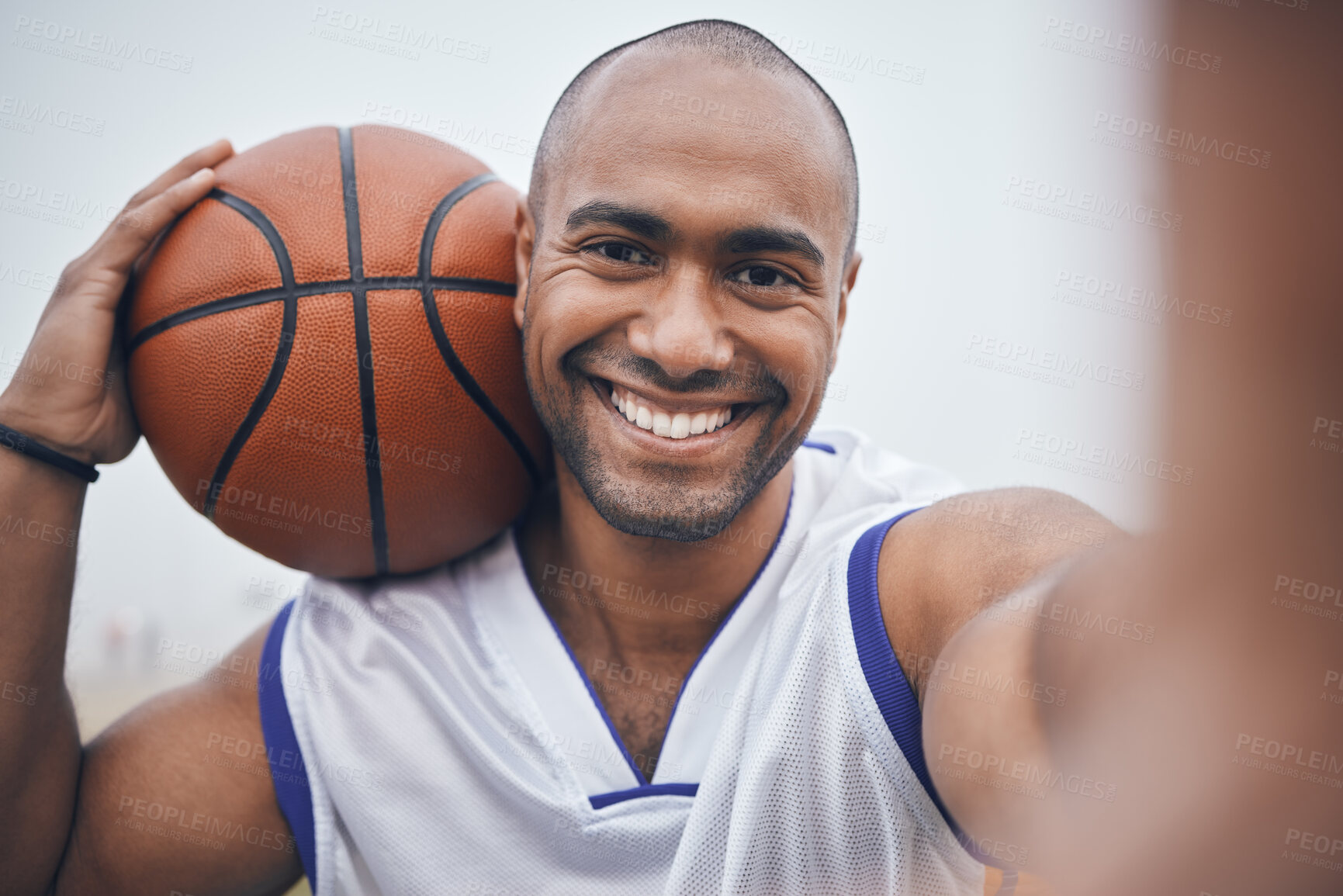 Buy stock photo Shot of a young male basketball player taking a selfie while holding the ball