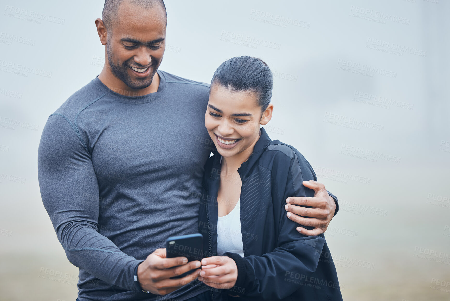 Buy stock photo Shot of a young couple spending time together during training while using a smartphone