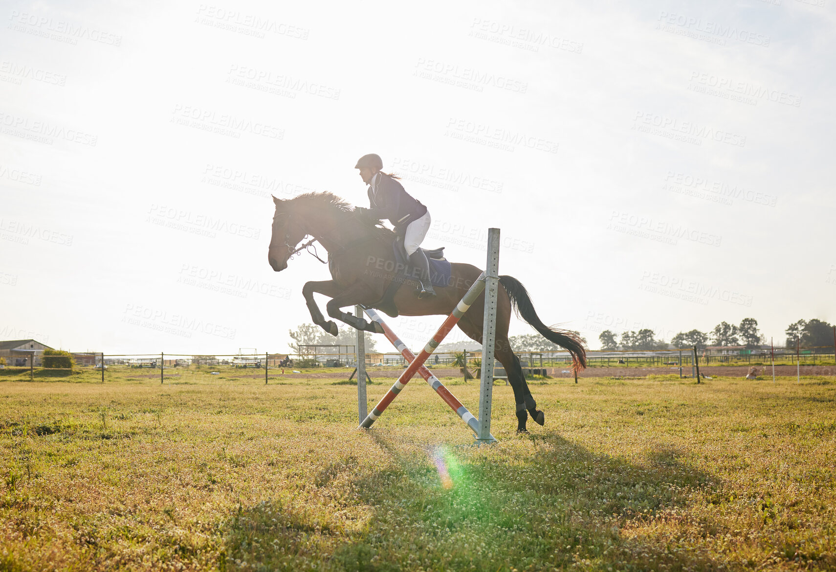 Buy stock photo Shot of a young rider jumping over a hurdle on her horse