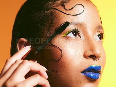 Buy stock photo Studio shot of a beautiful young woman holding a mascara brush against her face