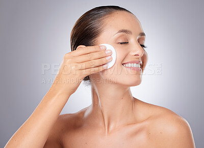 Buy stock photo Shot of a beautiful young woman wiping her face with cotton against a grey background