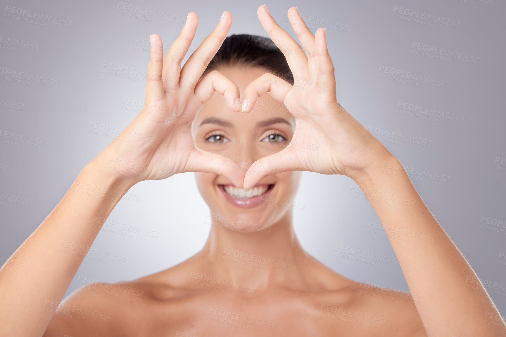 Buy stock photo Shot of a young beautiful woman making a heart gesture with her hands against a grey background