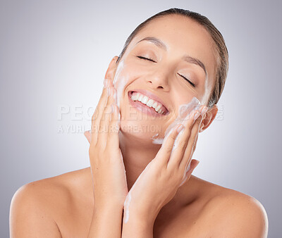 Buy stock photo Shot of a young beautiful woman washing her face against a grey background