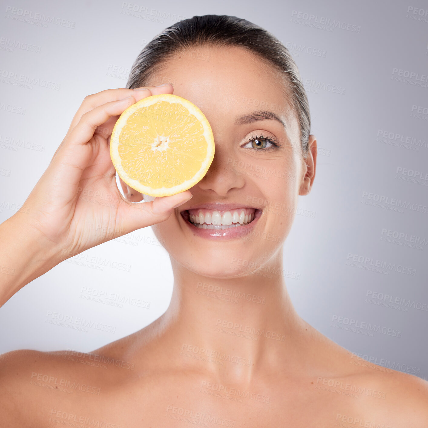 Buy stock photo Shot of a beautiful young woman holding a lemon against a grey background