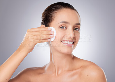 Buy stock photo Shot of a beautiful young woman wiping her face with cotton against a grey background