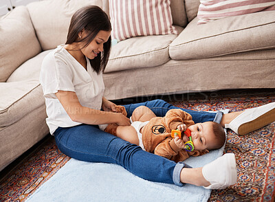 Buy stock photo Shot of a young mother dressing her son while he chews a toy
