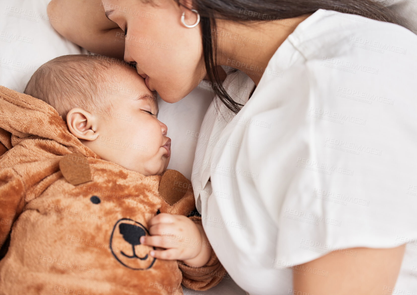 Buy stock photo Shot of a young mother kissing her sons forehead while he sleeps