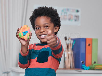 Buy stock photo Shot of a young boy showing thumbs up while holding play dough