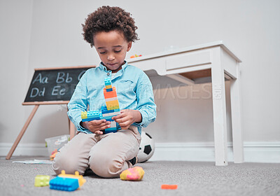 Buy stock photo Shot of a young boy playing with building blocks in a room