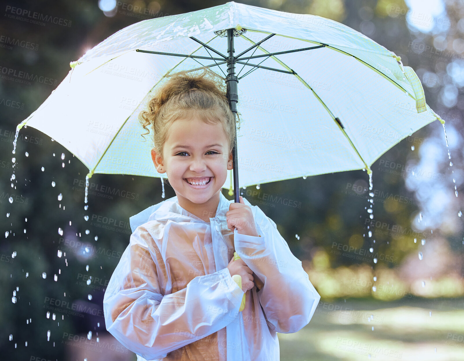 Buy stock photo Shot of a little girl playfully standing in the rain holding her umbrella