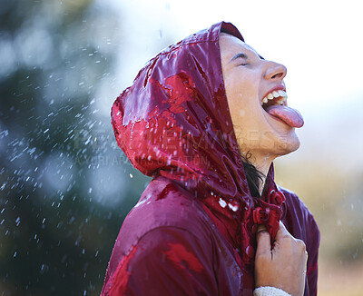 Buy stock photo Shot of a young woman sticking out her tongue to feel the rain outside