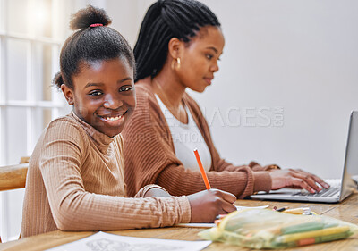 Buy stock photo Shot of a young mother using a laptop while her daughter does homework at home