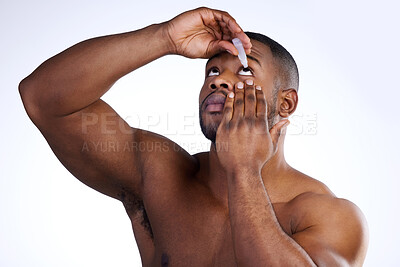 Buy stock photo Studio shot of a handsome young man applying eyedrops against a white background