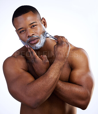 Buy stock photo Studio portrait of a handsome young man shaving against a white background