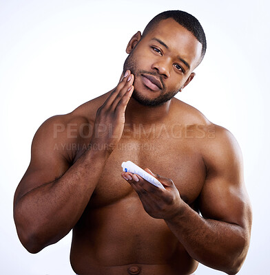Buy stock photo Studio portrait of a handsome young man moisturizing his face against a white background