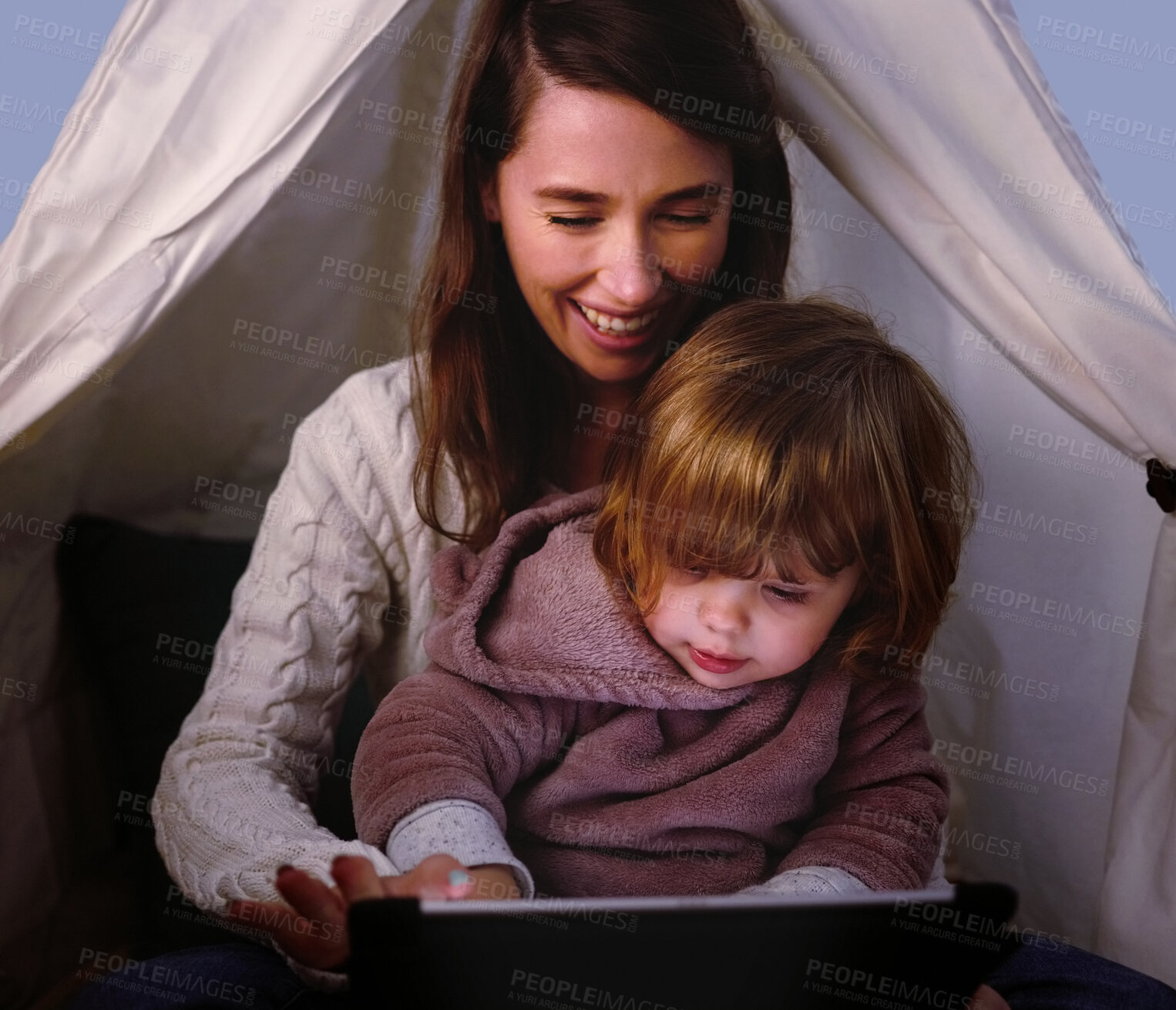 Buy stock photo Shot of a little girl using a digital tablet while sitting at home with her mother