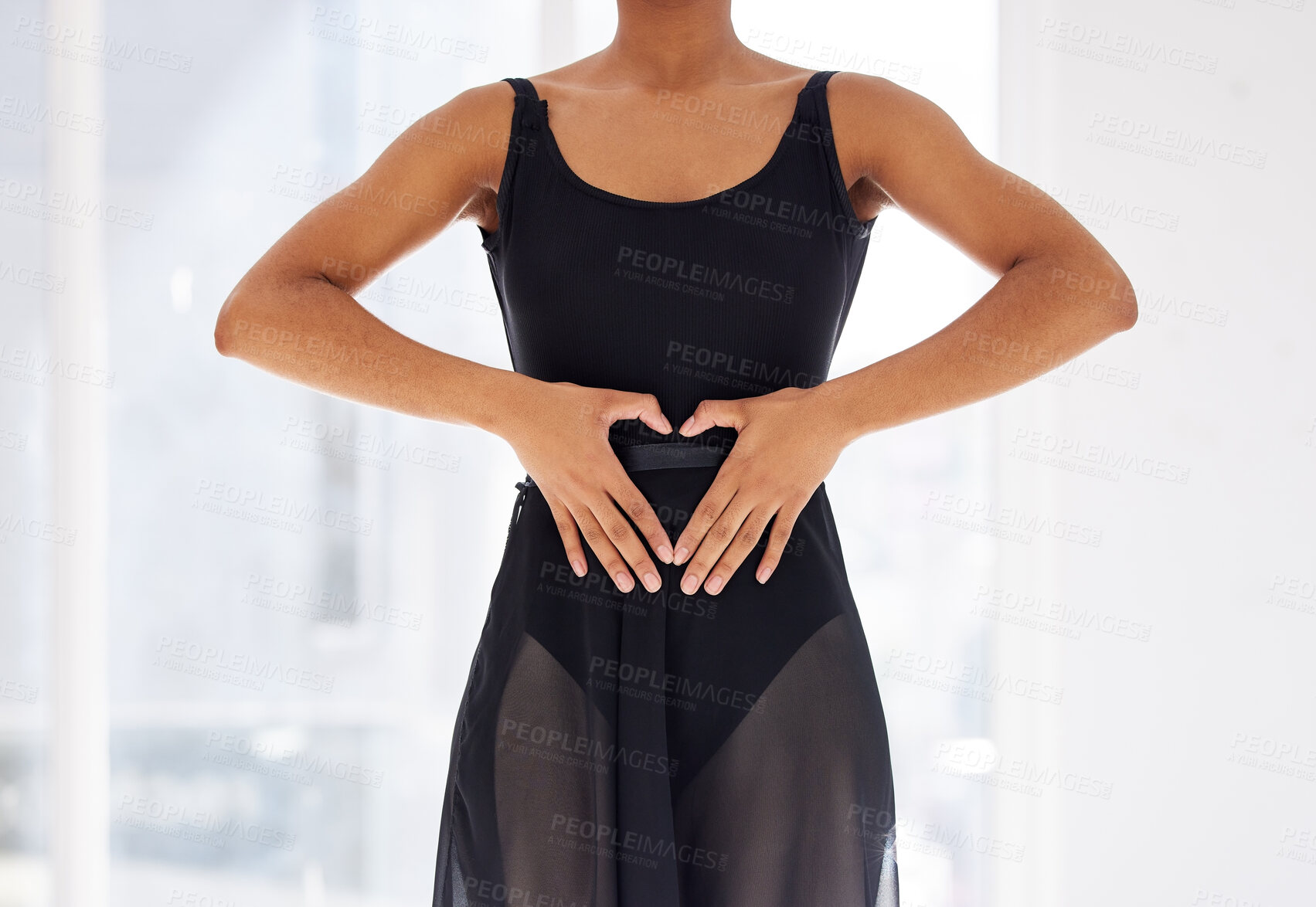 Buy stock photo Shot of a ballerina creating a heart shape with her fingers over her stomach