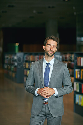 Buy stock photo Cropped portrait of a handsome young businessman standing with his hands together in an empty library
