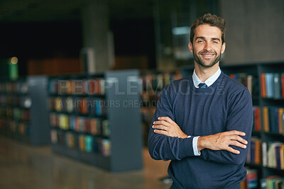 Buy stock photo Cropped portrait of a handsome young businessman standing with his arms crossed in an empty library