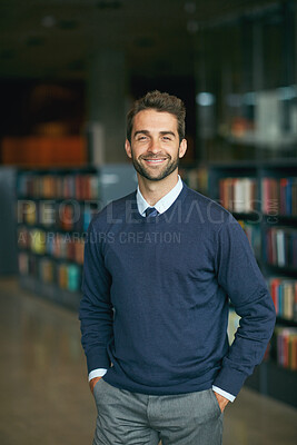 Buy stock photo Cropped portrait of a handsome young businessman standing with his hands in his pockets in an empty library