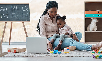 Buy stock photo Shot of a little girl watching something on a laptop while sitting on her mother's lap