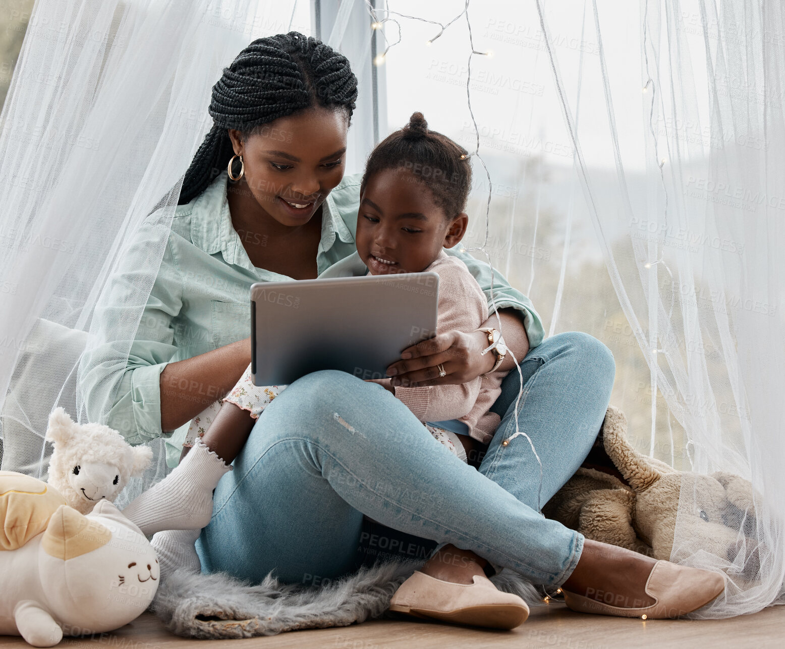 Buy stock photo Shot of a woman using a digital tablet while sitting with her daughter