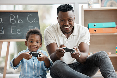 Buy stock photo Shot of a little boy and his dad playing video games at home