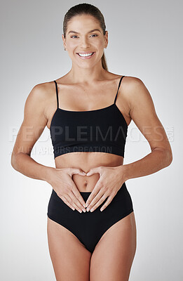 Buy stock photo Gut health, portrait and woman in underwear in studio for love, confidence and wellness. Smile, digestion and happy girl in sportswear for heart hands, weight loss or diet results on white background