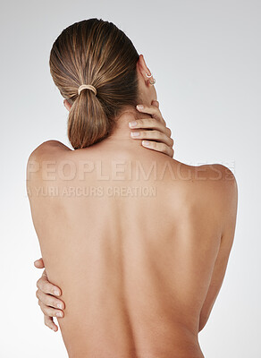 Buy stock photo Rearview studio shot of a young woman embracing her body against a grey background