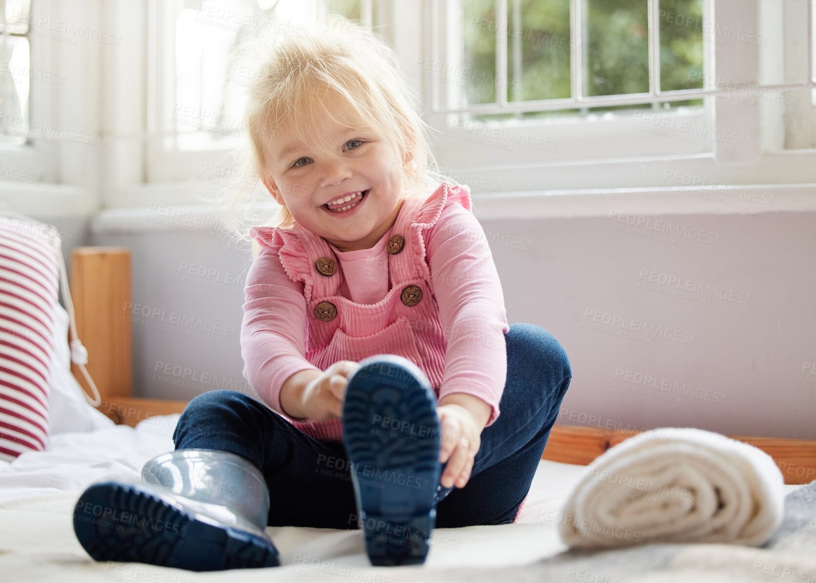 Buy stock photo Shot of a little girl putting on her boots at home
