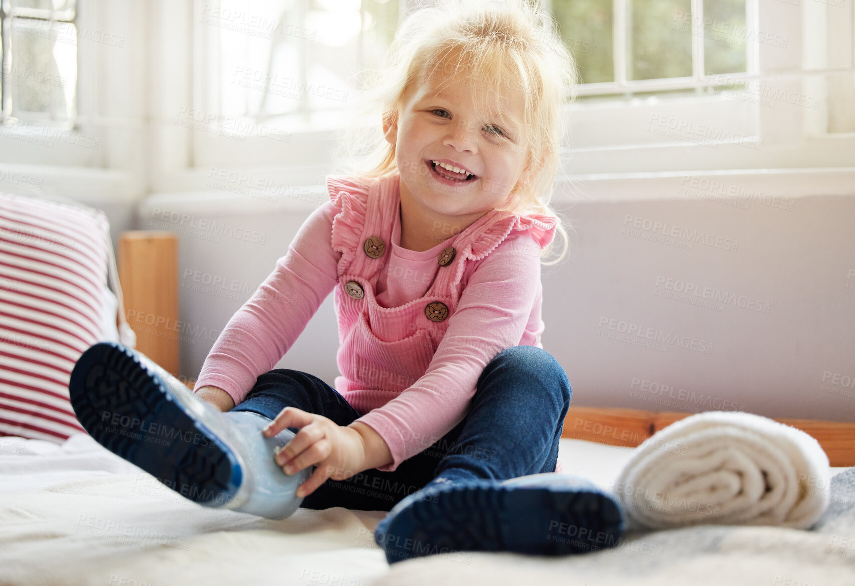 Buy stock photo Shot of a little girl putting on her boots at home