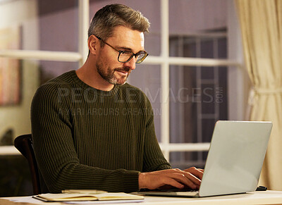 Buy stock photo Cropped shot of a handsome mature businessman working on his laptop at home