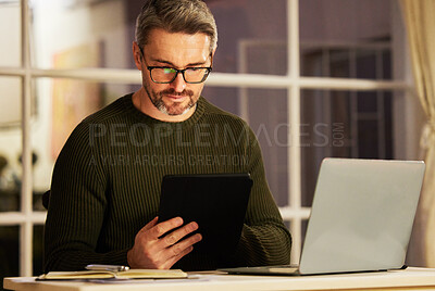 Buy stock photo Cropped shot of a handsome mature businessman working on his laptop and tablet at home