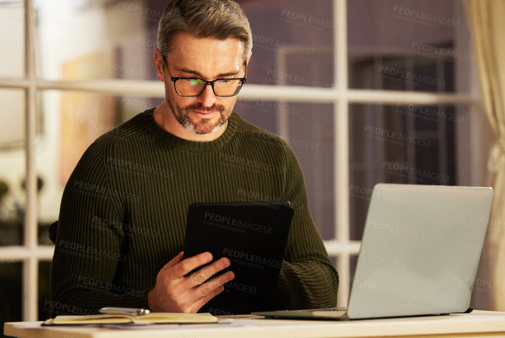 Buy stock photo Cropped shot of a handsome mature businessman working on his laptop and tablet at home